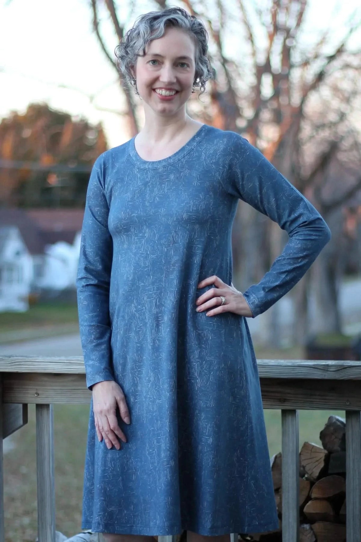 A woman in a blue dress with a white geometric pattern smiles at the camera.