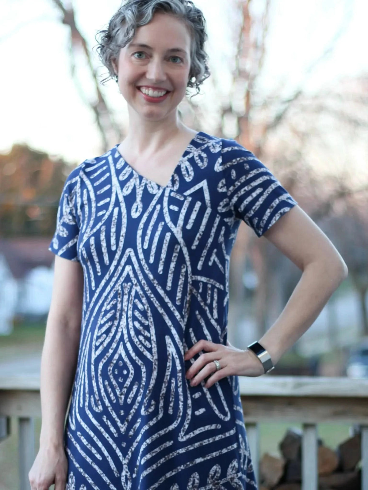 A woman in a blue and white patterned dress smiles at the camera.