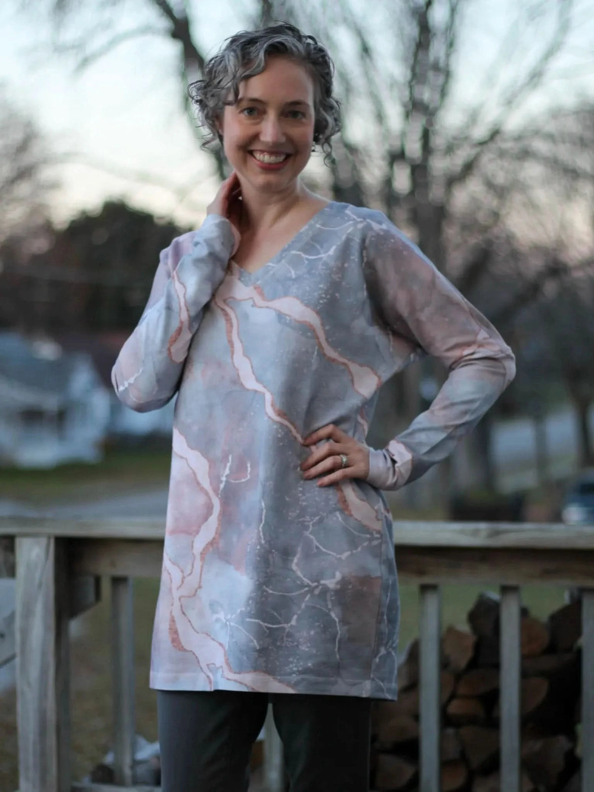 A woman models a long-sleeved tunic in a pink and gray marble pattern.