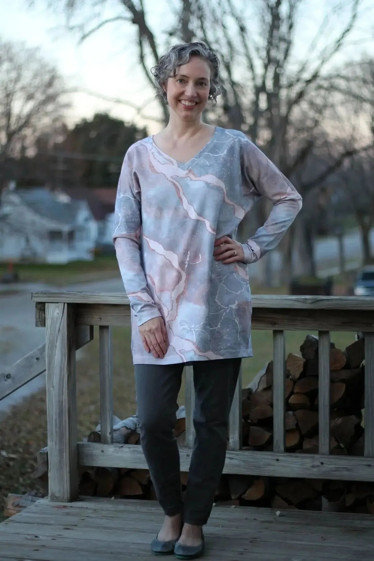A woman models a long-sleeved tunic with a pink and gray marble pattern.
