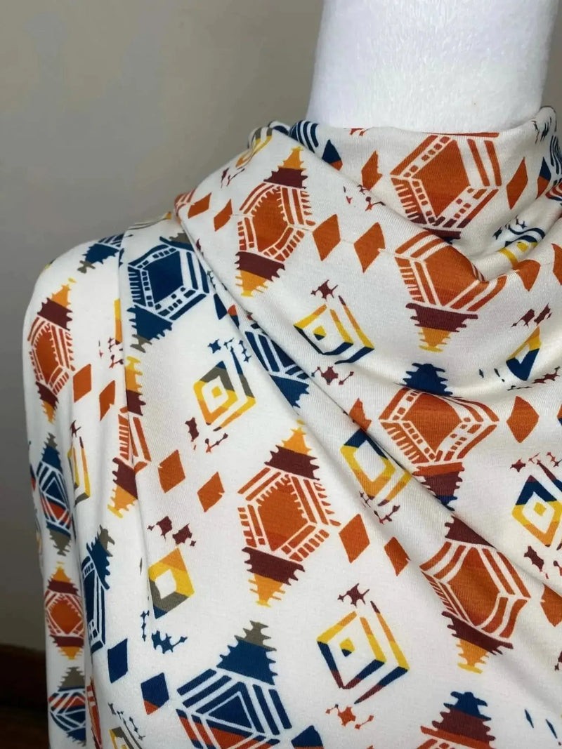 White fabric with orange, navy, and yellow diamond geometric print draped on a mannequin.