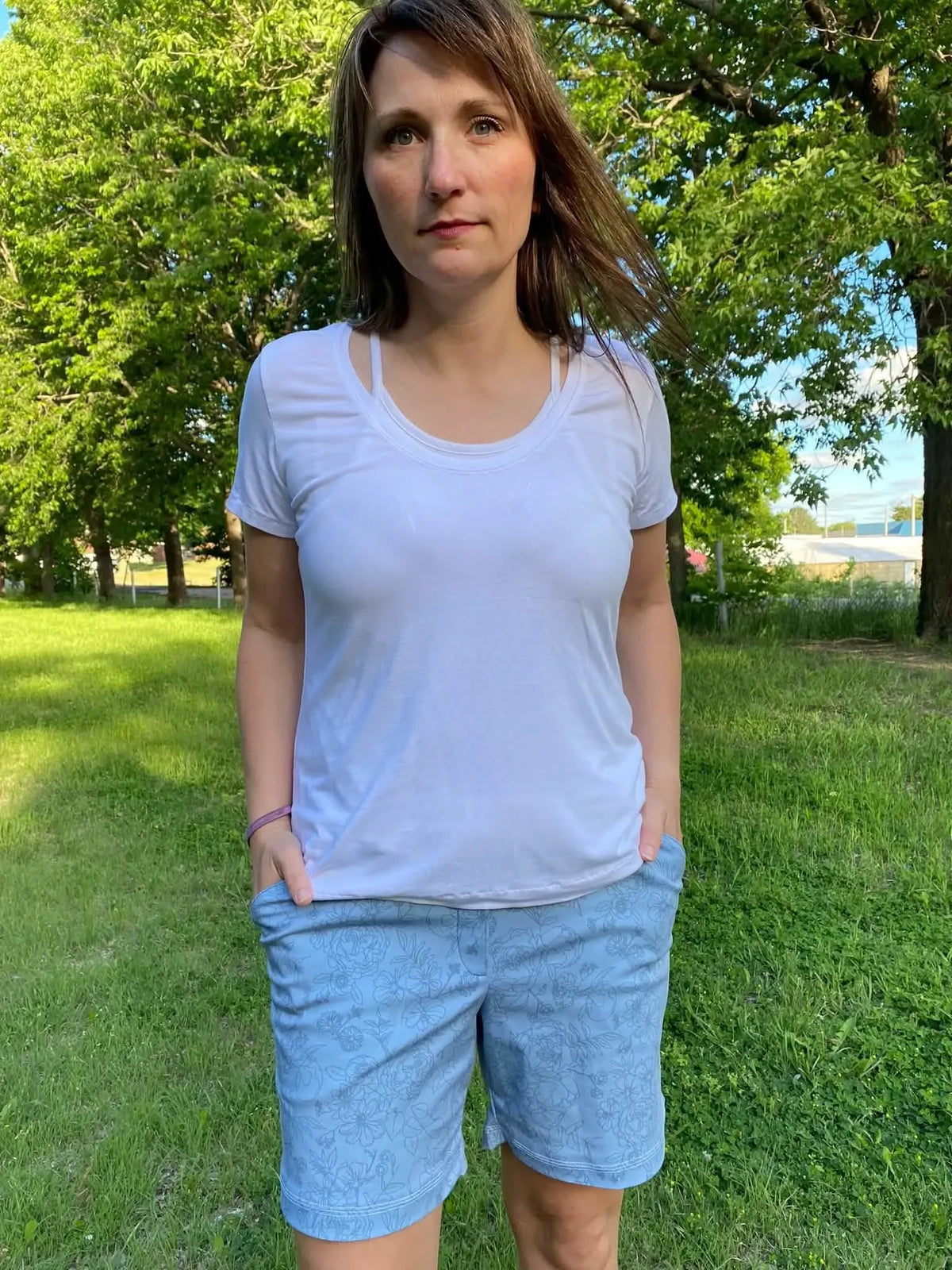 A woman wears dusty blue stenciled floral shorts and a white t-shirt.