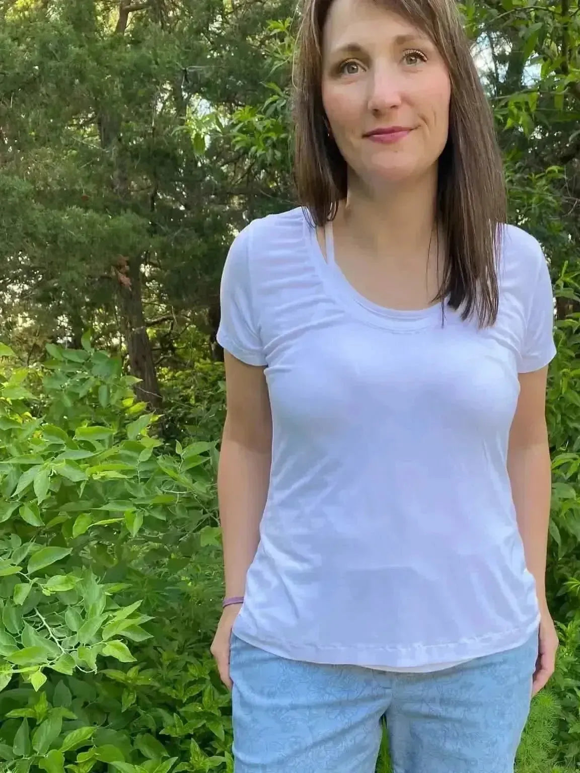 Dusty blue fabric with stenciled floral pattern, shown as a white top and pants on a model in greenery.