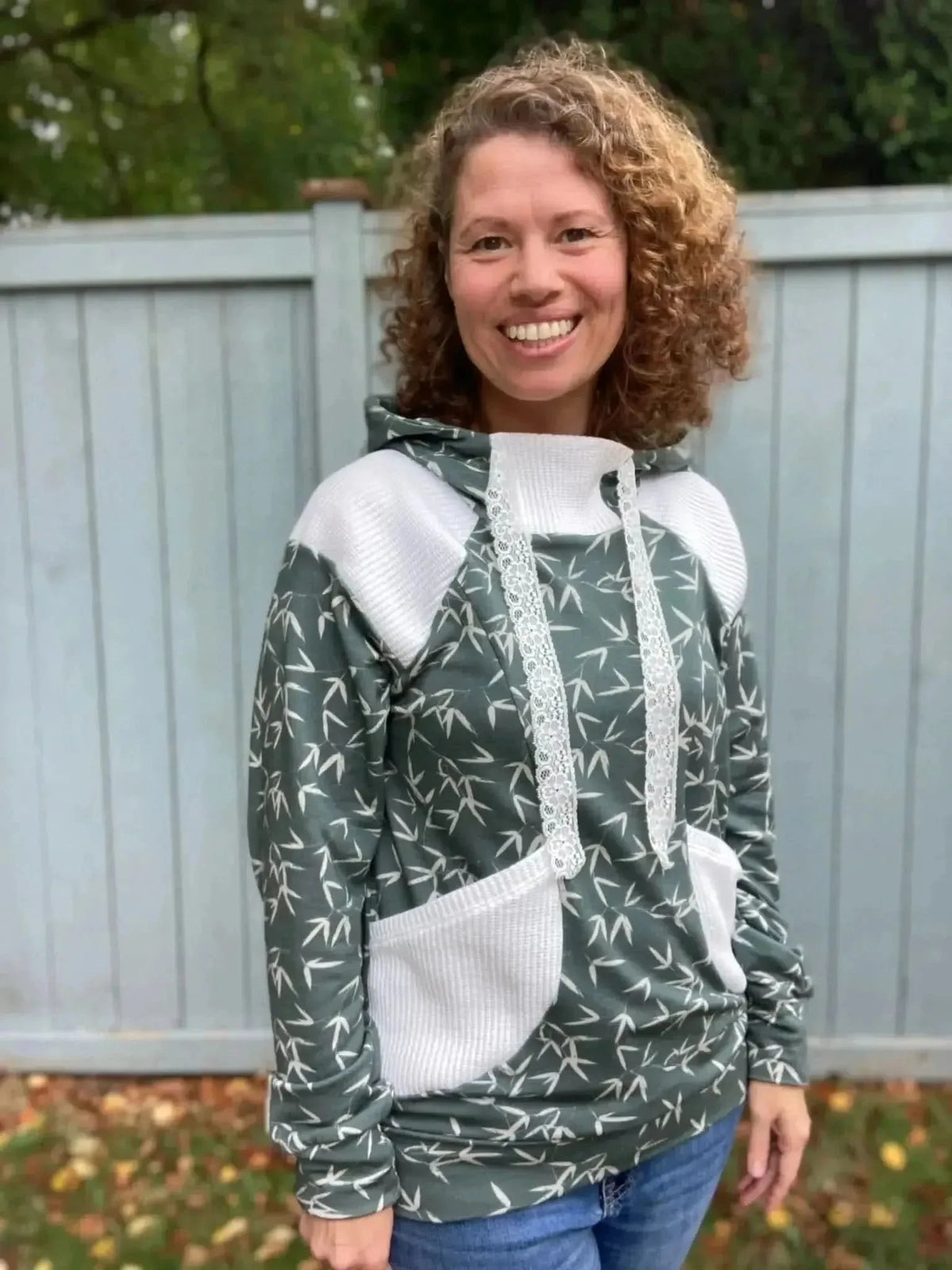 Green hooded sweatshirt with white accents and bamboo leaf print, modeled outdoors.