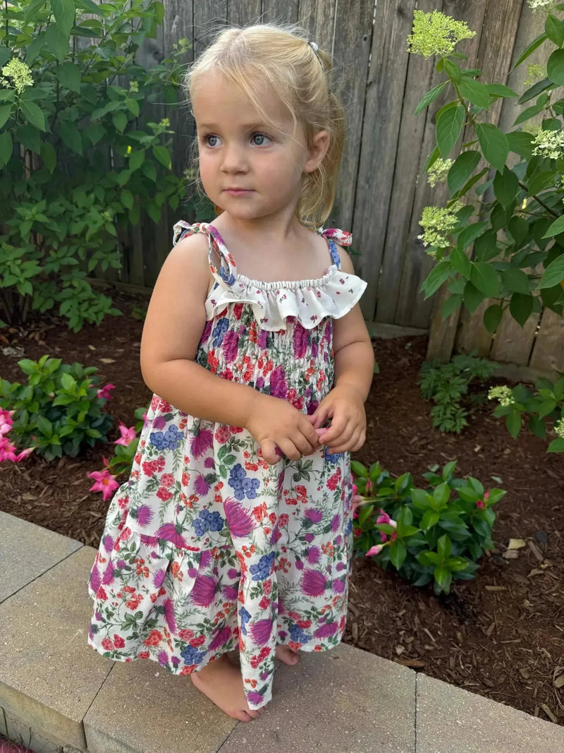 Floral print fabric featuring thistle field pattern in pink, purple, and white on a cream background.