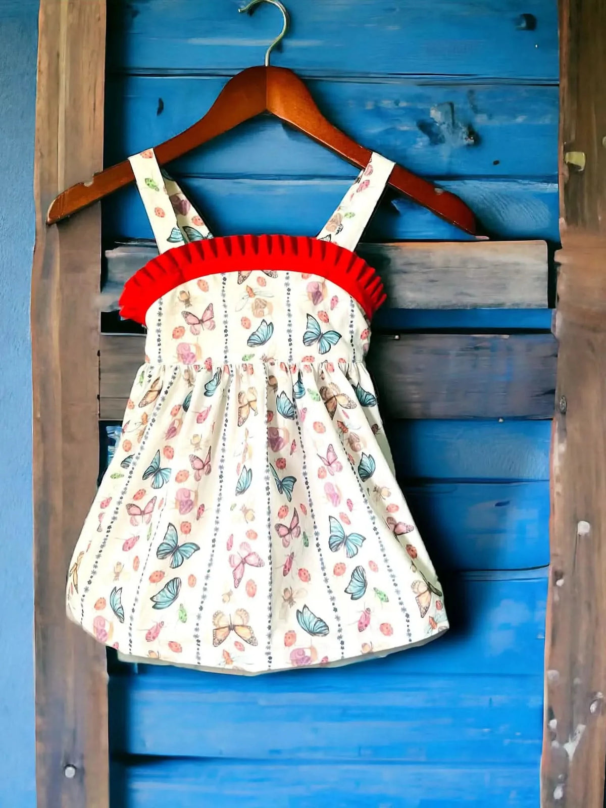 A white dress with a red ruffled top and a pattern of colorful butterflies and bugs.