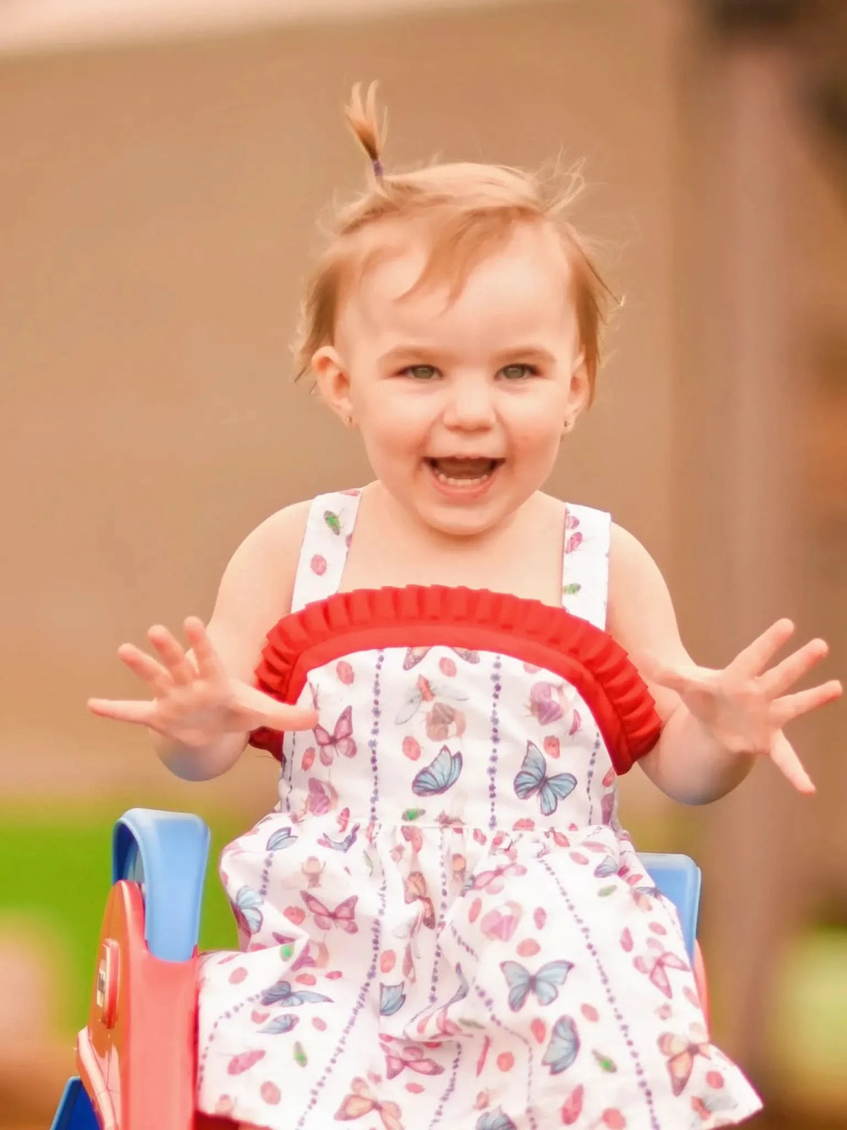 A young child in a white dress with colorful bug and butterfly patterns.
