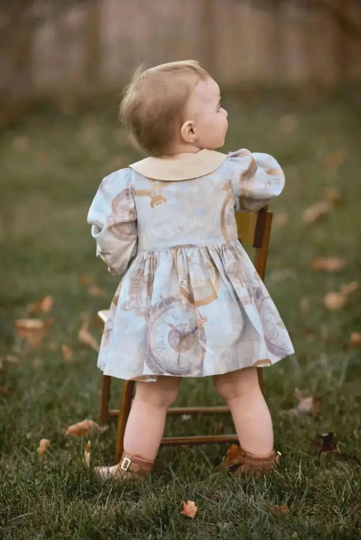 Blue fabric with gold clock print and faith-based motifs, shown in a child's dress.