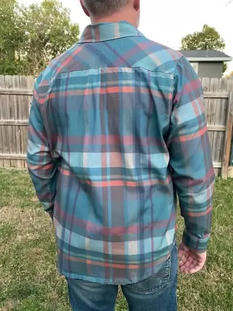 A person from behind wears a blue, orange, and gray plaid long-sleeved shirt.