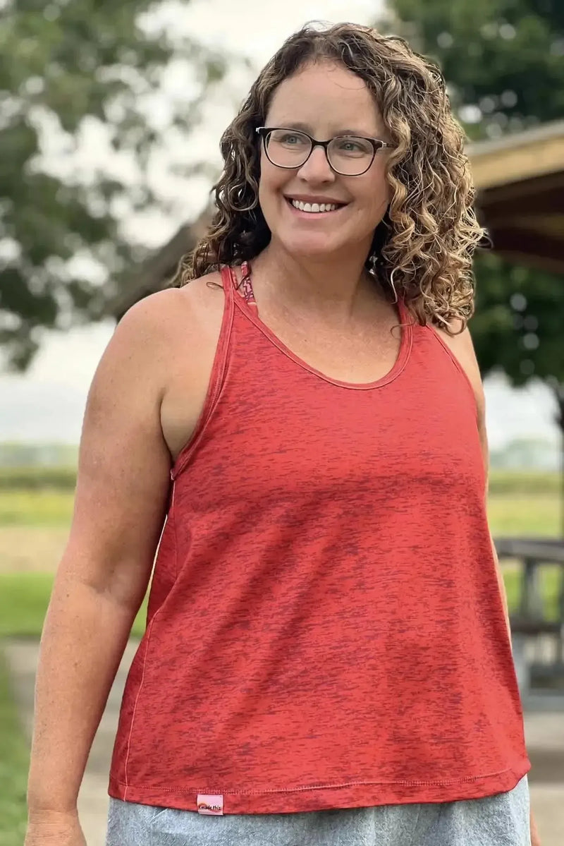 A woman smiles, wearing a red heather activewear tank top.