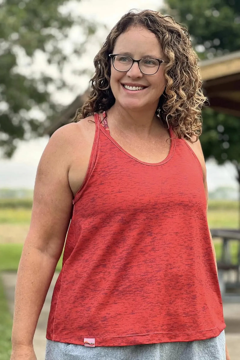 A woman smiles, wearing a red heathered tank top with a small "I made this" tag.