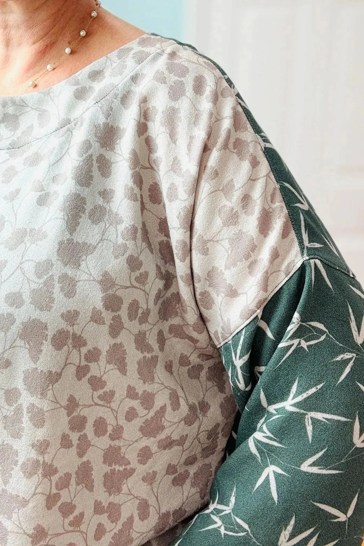 Green leaf print fabric with light gray and green tones on a nature-inspired pattern.
