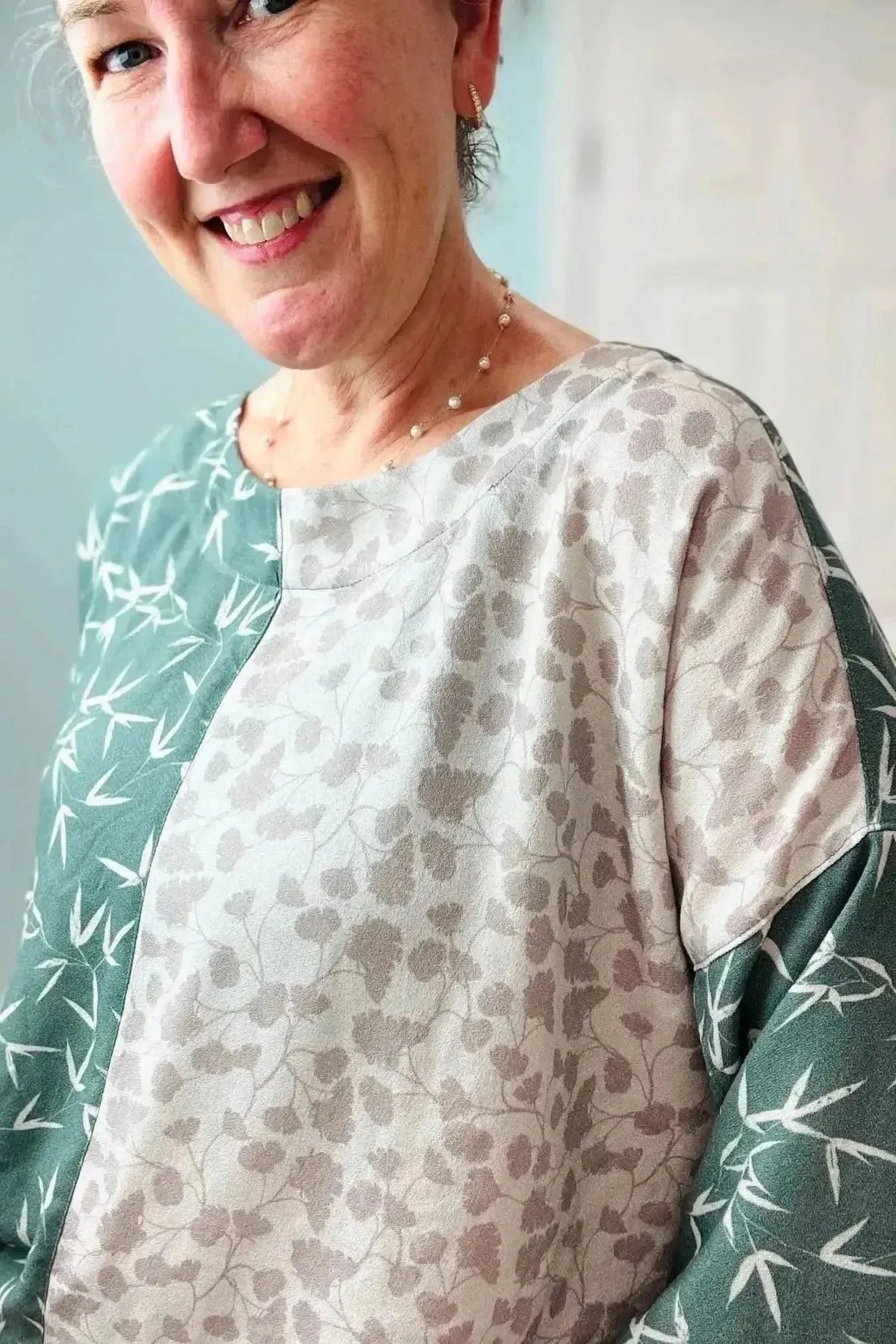 Green leaf print fabric with light gray and aqua tones on a neutral background.