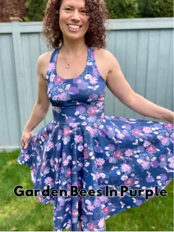 A woman smiles while wearing a navy blue dress with a purple floral and bee pattern.