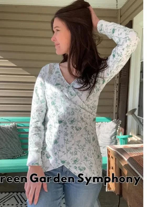 A woman models a white long-sleeved top with a green floral pattern.