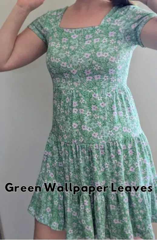 A woman models a green floral dress with a square neckline and ruffled hem.
