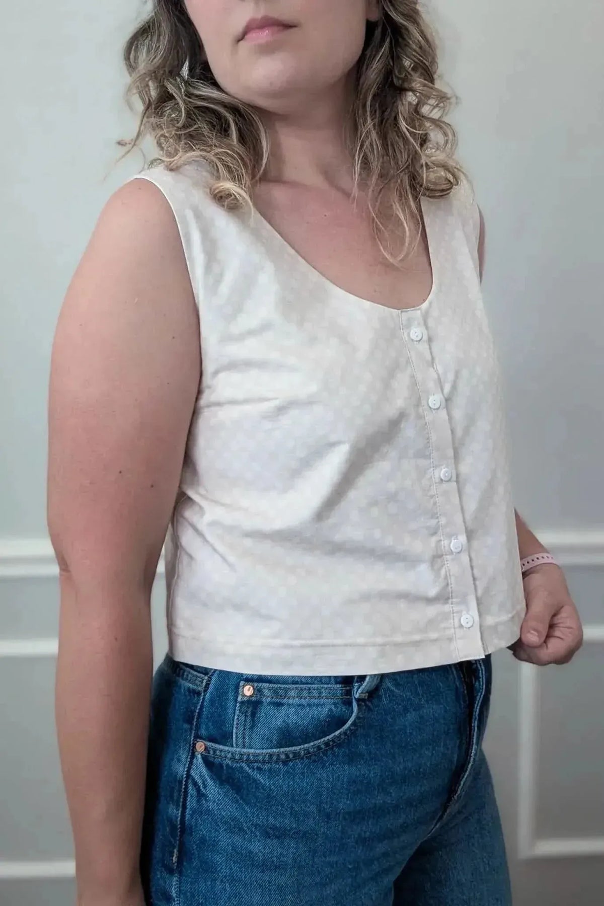 Light beige polka dot fabric swatch on a sleeveless button-up top.