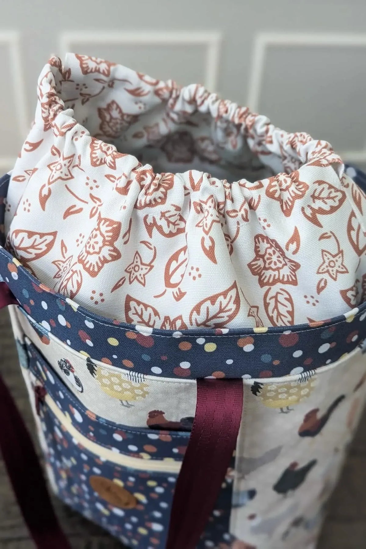 A fabric bag with a drawstring top featuring a folk flower pattern.