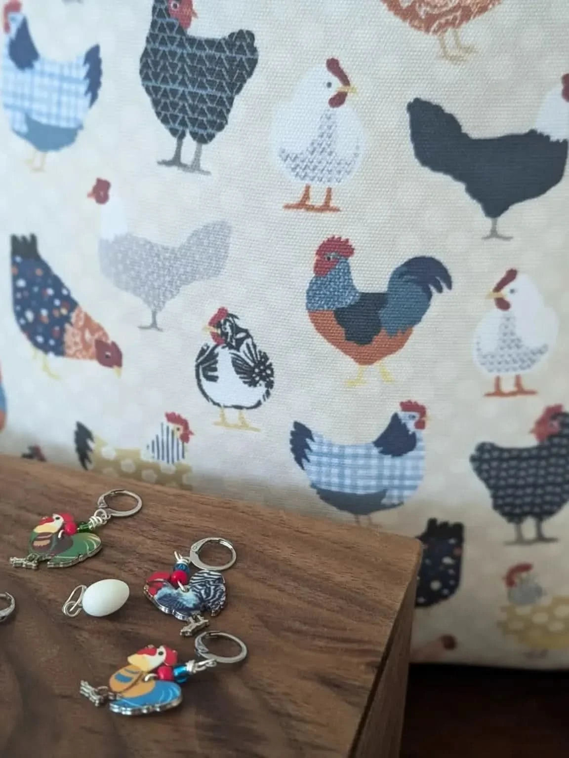 A fabric with various colorful chicken illustrations and several chicken-themed keychains.