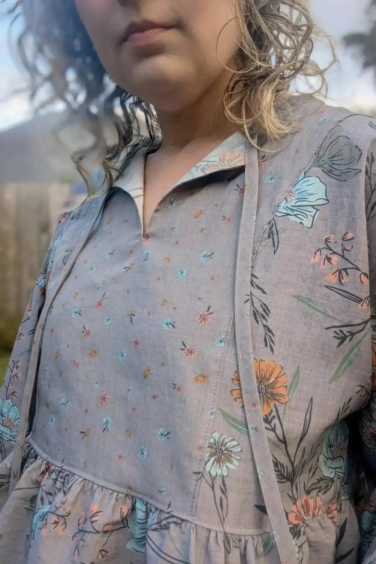 Taupe floral print fabric with small blooms in pink, blue, and orange on gray.