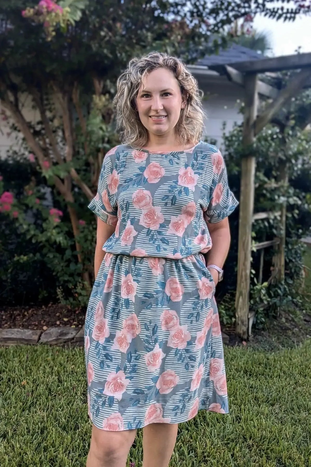 A woman wears a dress with a pink rose and striped pattern.