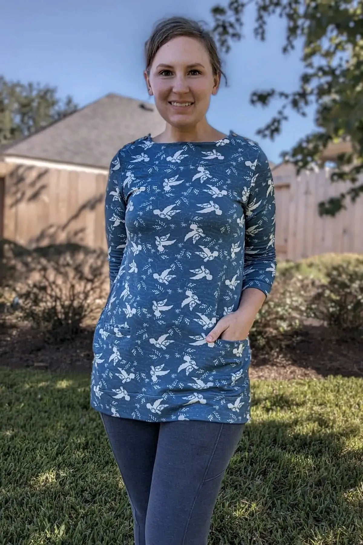 Woman in a blue long-sleeve tunic with white dove print and dark leggings.