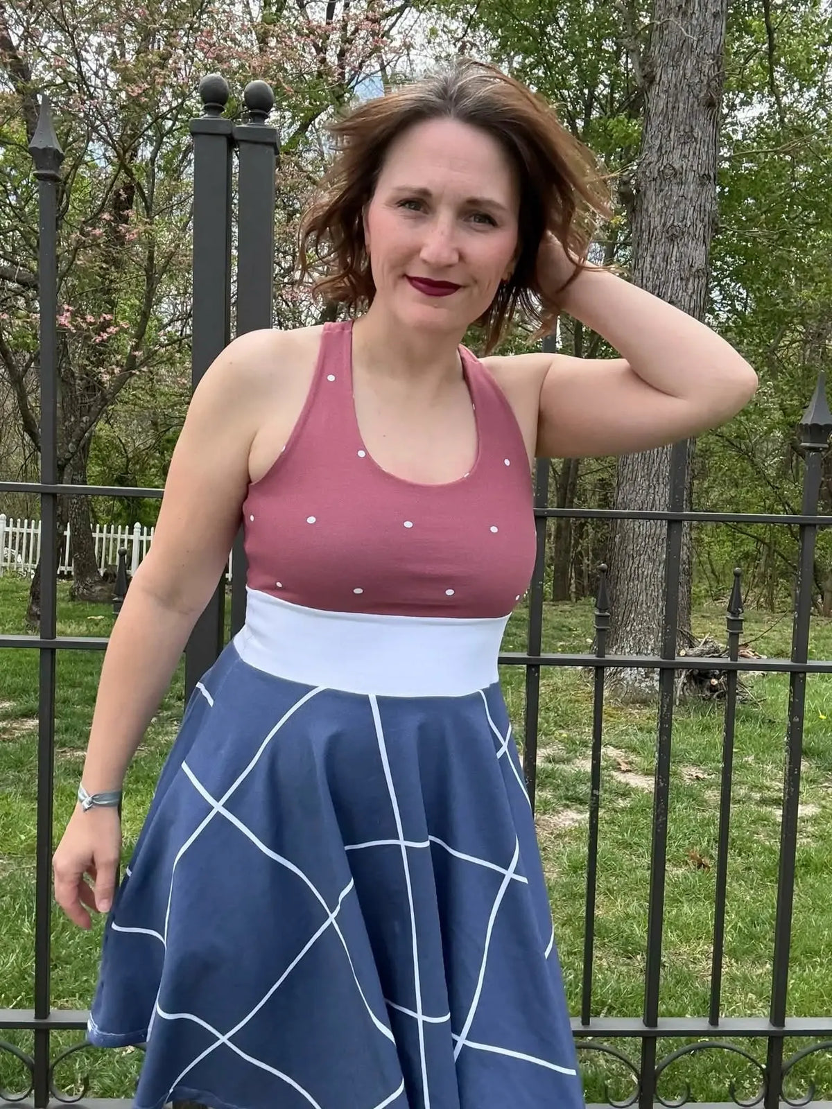 A woman wears a navy windowpane skirt and a pink polka dot top.