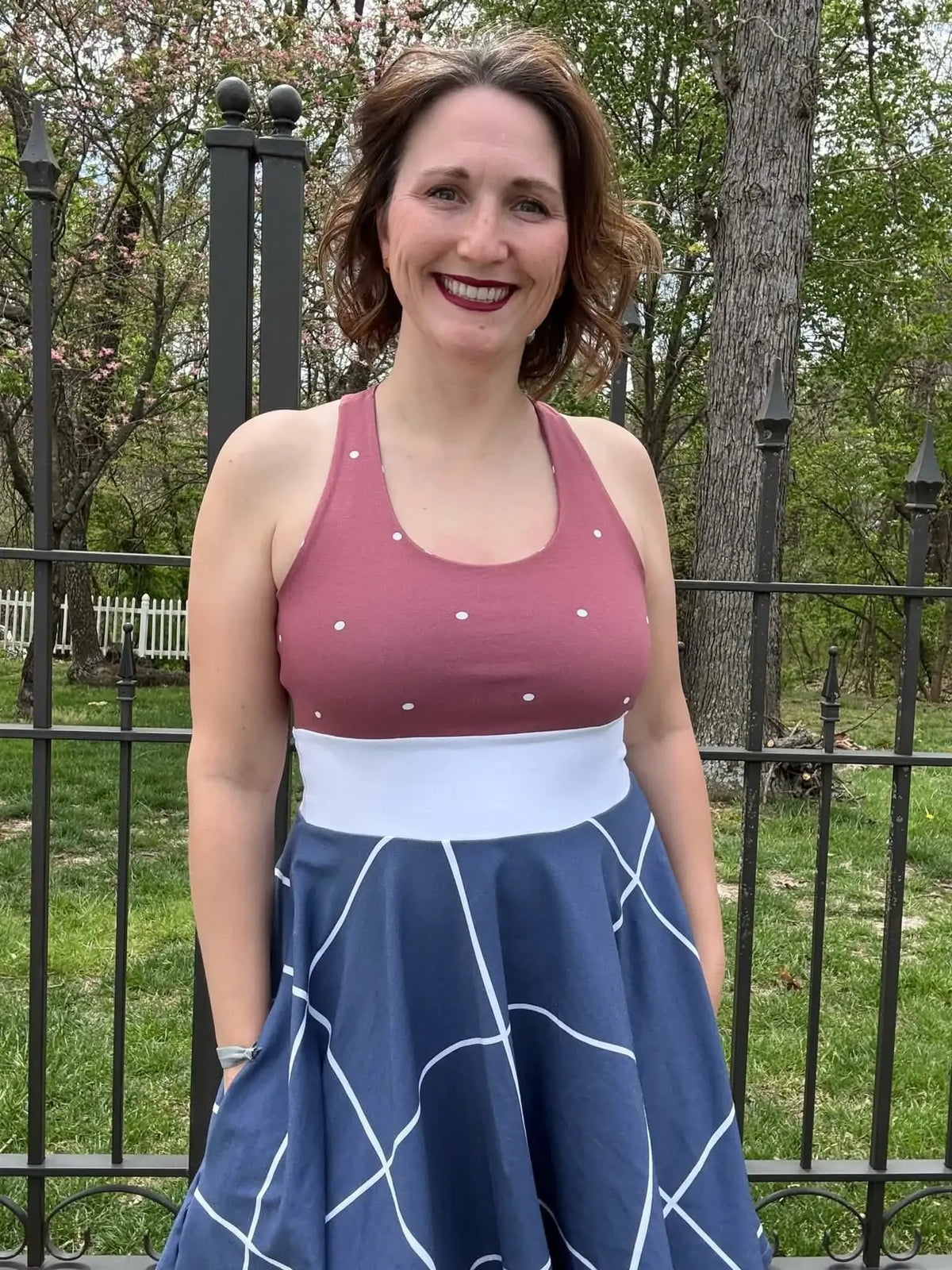 A woman wears a dress with a polka dot top and a navy windowpane skirt.