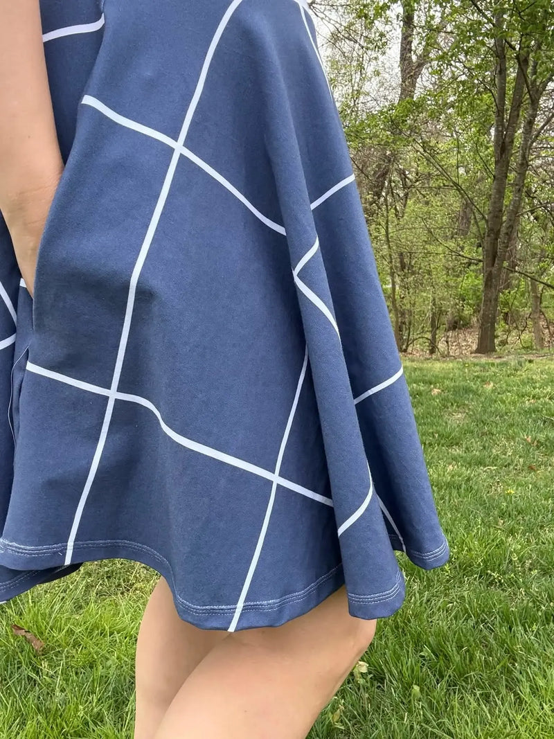 Navy windowpane fabric draped over a person's legs in a grassy outdoor setting.