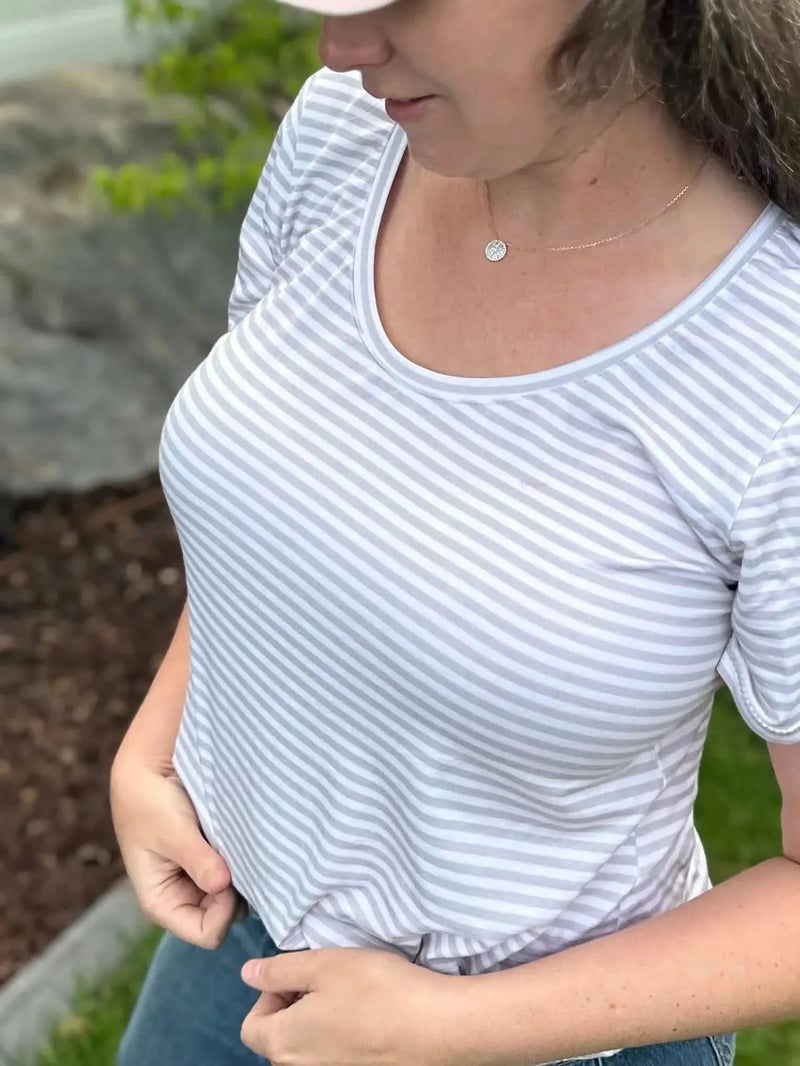 A woman wears a light gray and white striped short-sleeved shirt.