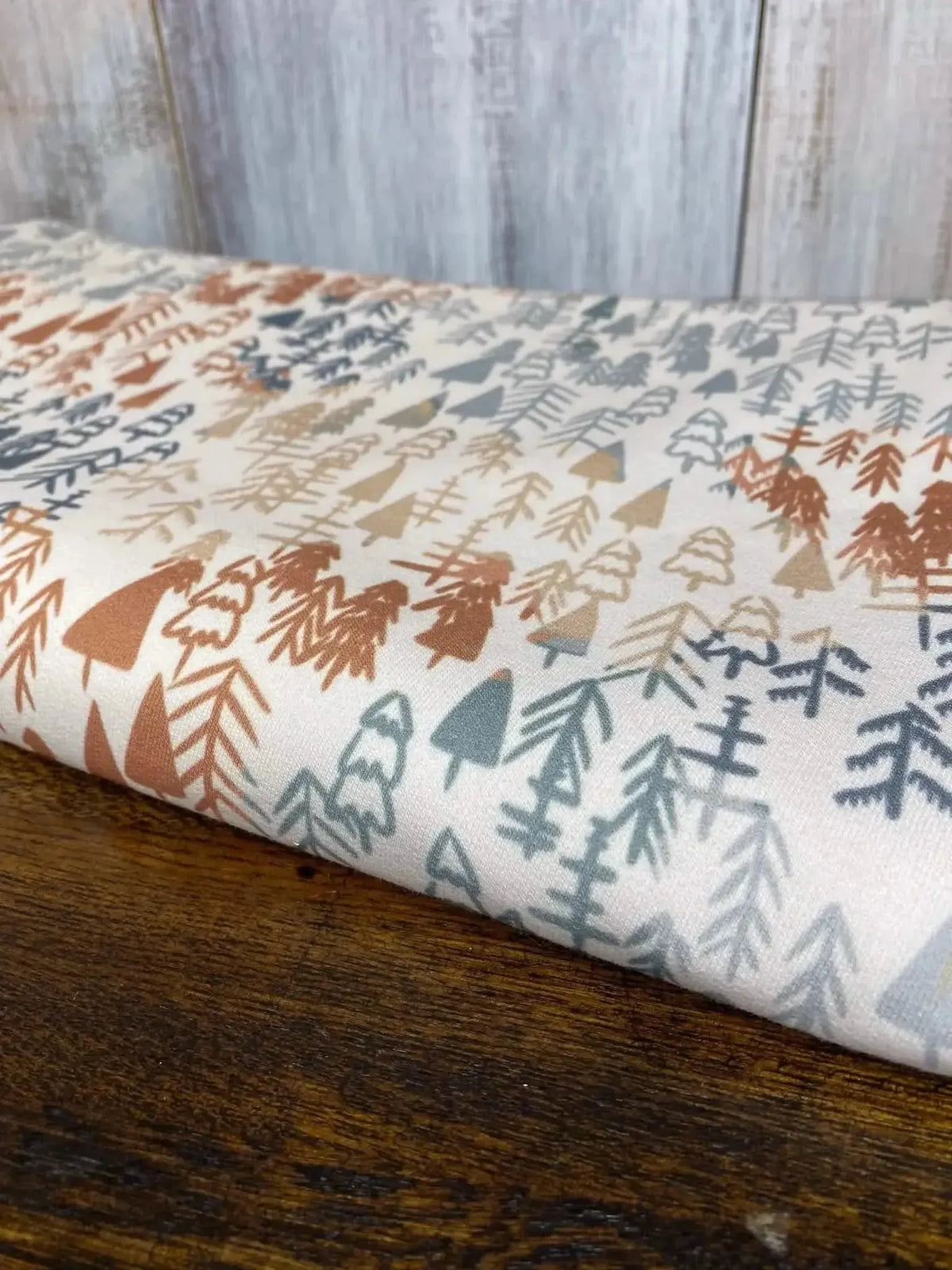 Light fall trees autumn forest print fabric in soft beige with multicolored trees.