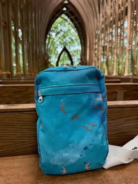 Dark teal bag with orange bird silhouettes on a wooden bench.