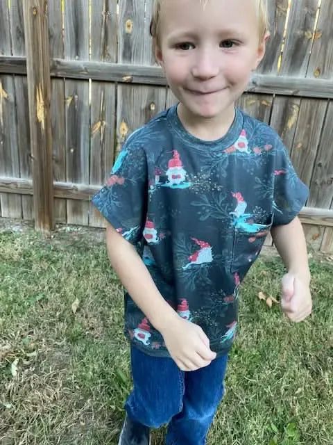 A young boy wears a green shirt with a gnome toile pattern.