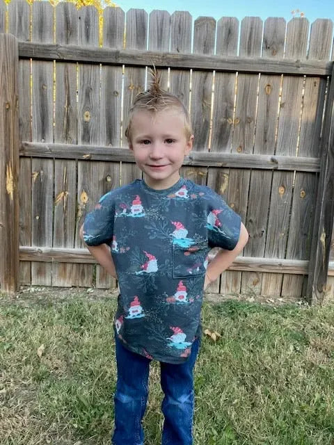 A young boy wears a dark green shirt with a gnome toile pattern.
