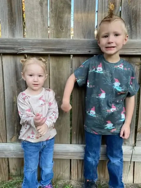 Two children wear clothing made from Gnome Toile in Green fabric.