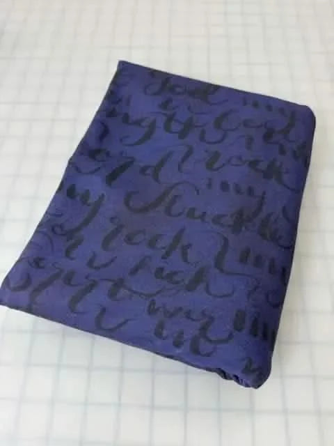 A folded piece of dark blue fabric with black script lettering.