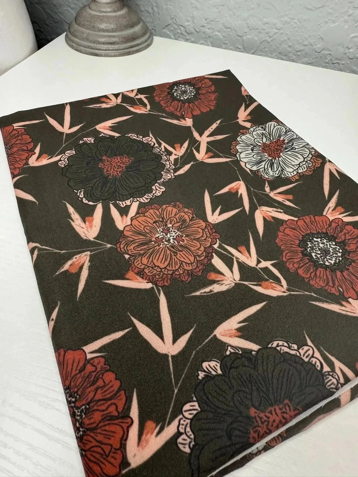 Dark brown fabric with intricate red and white floral and stem print.