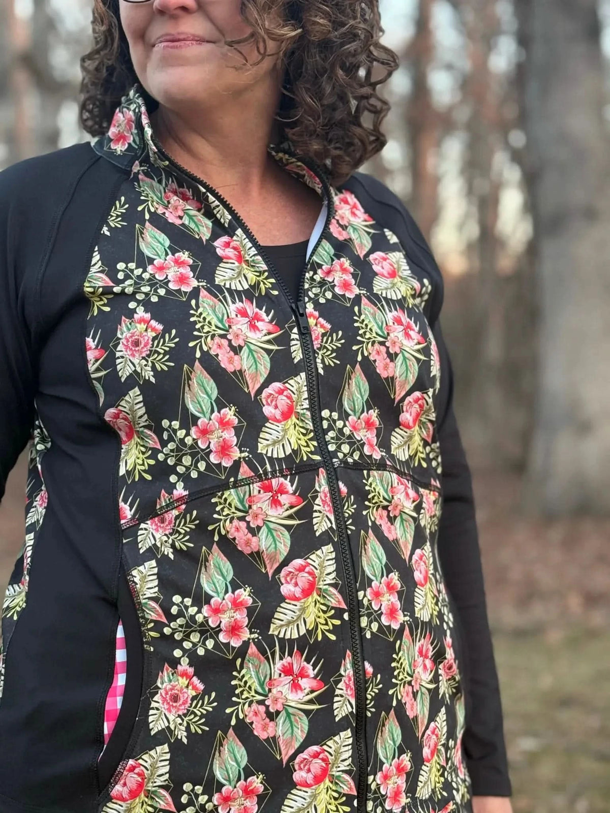 A woman wears a black jacket with a floral and geometric pattern.