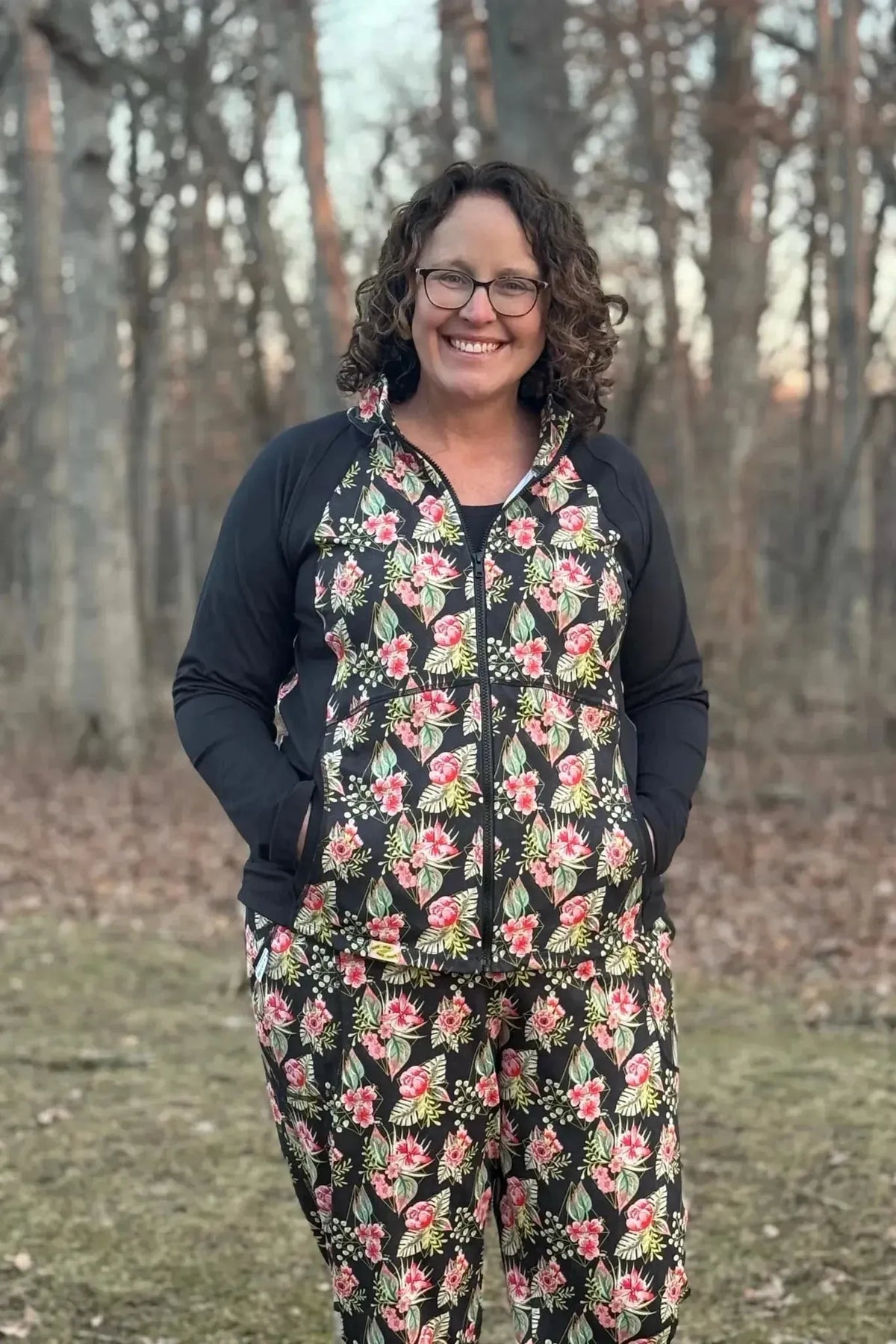 Woman wearing a black hoodie and pants with pink floral tropical print.