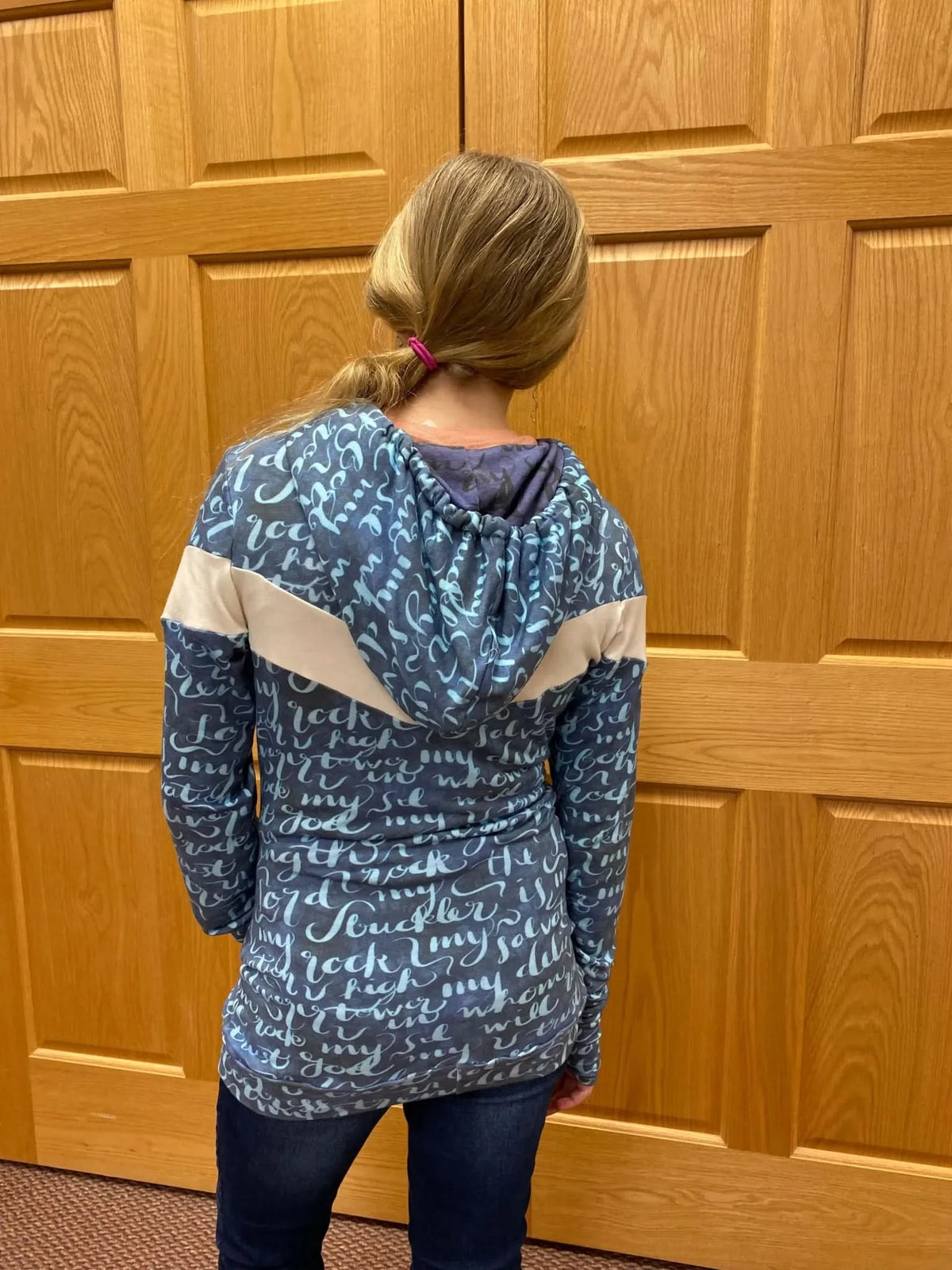 A person from behind wearing a blue and white patterned hoodie and jeans.