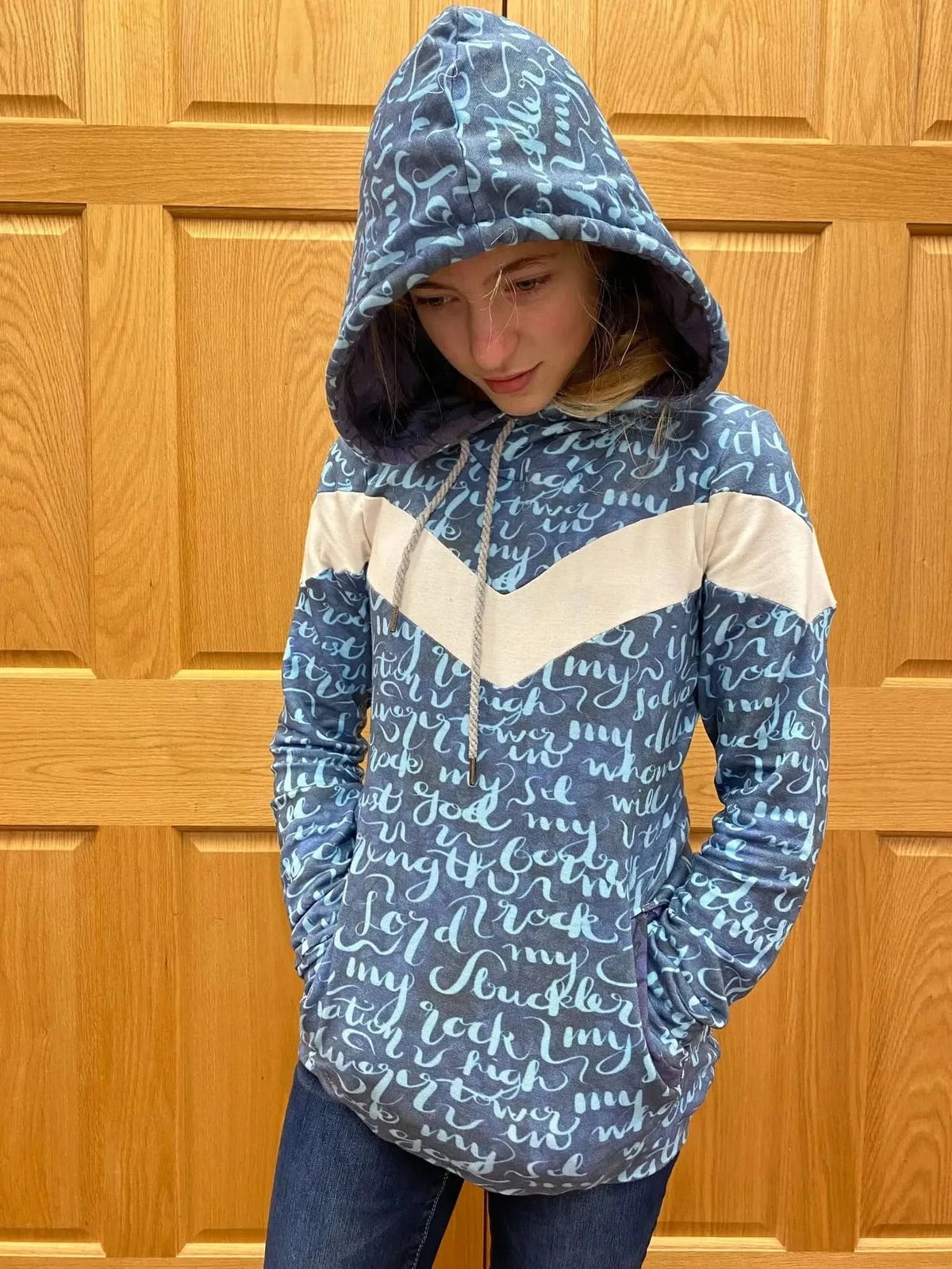 A young person wears a blue hoodie with white chevron stripes and script text.