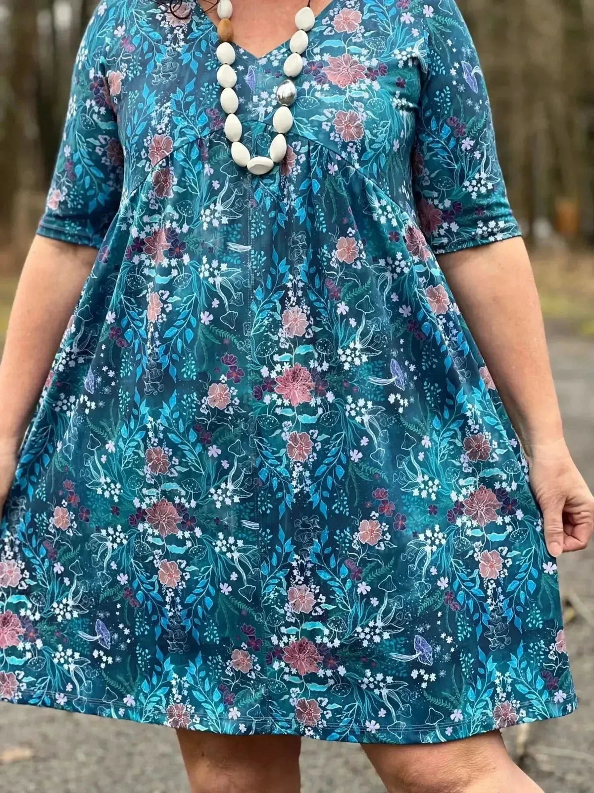 Teal woodland print fabric with flowers and mushrooms.