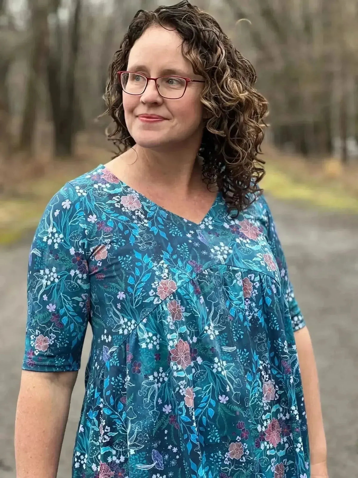 A woman in a teal woodland print dress with short sleeves and a v-neck.