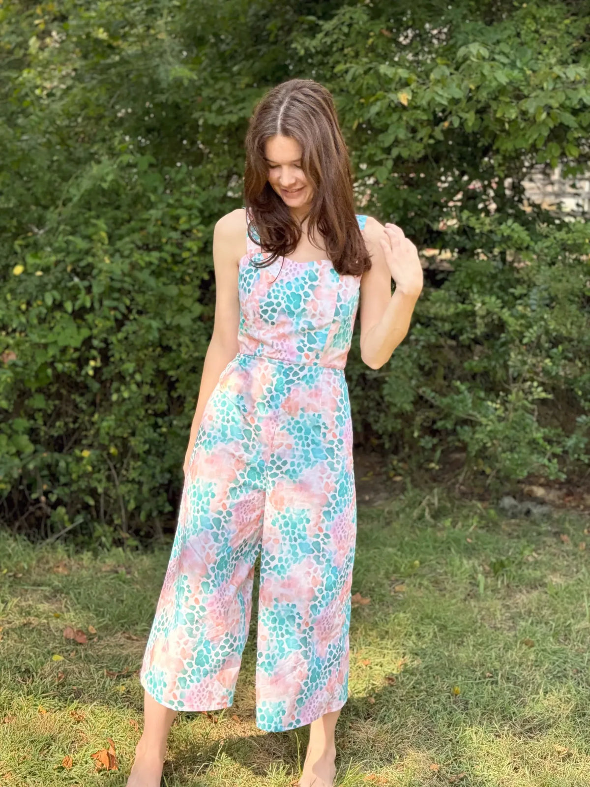 A woman models a colorful, patterned jumpsuit with a sweetheart neckline.