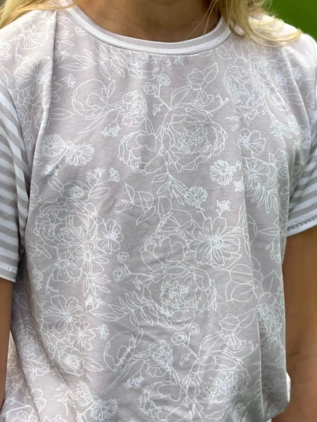 Tan stenciled floral fabric with white outlines of flowers and leaves.