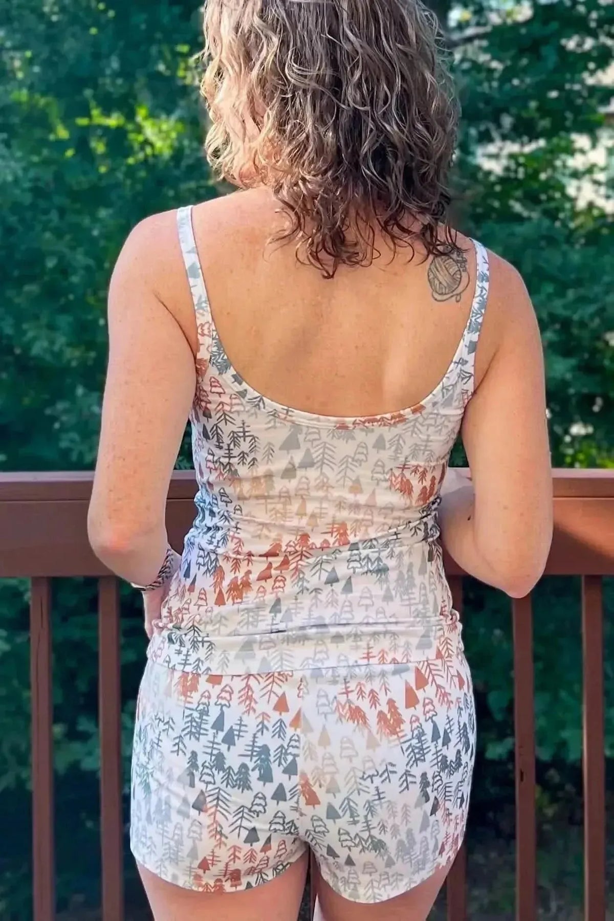 Rear view of a woman modeling a two-piece set in light fall trees autumn forest print fabric.