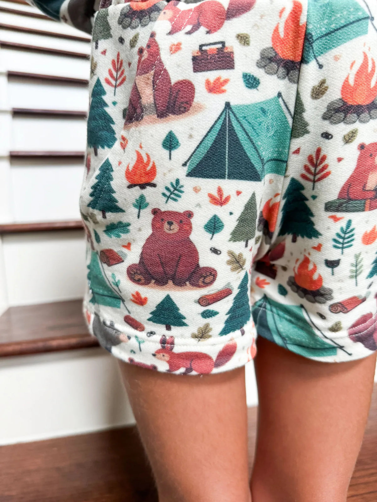 A child wears shorts with a camping bears print.