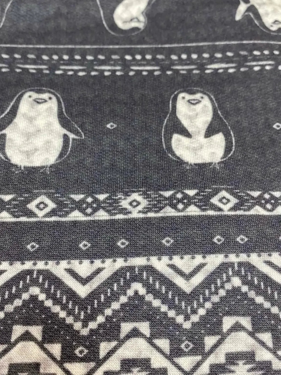 Dark gray fabric with white penguins and geometric patterns.