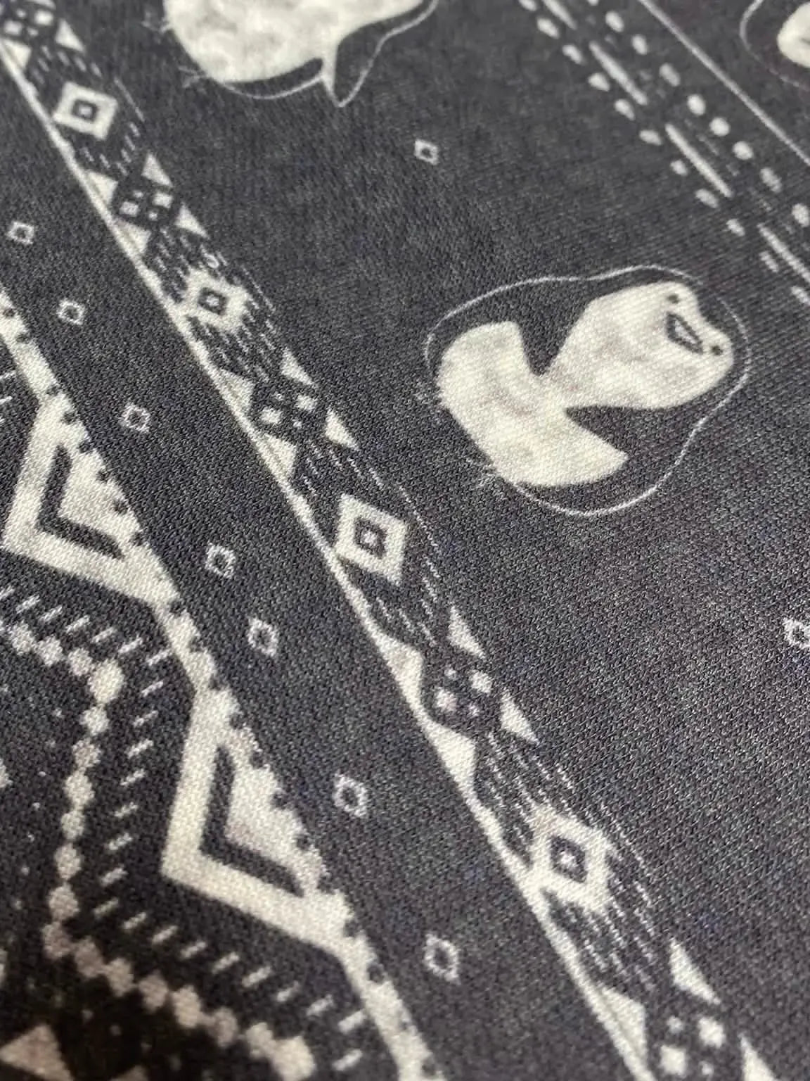 Dark fabric with white geometric patterns and cartoon penguins.