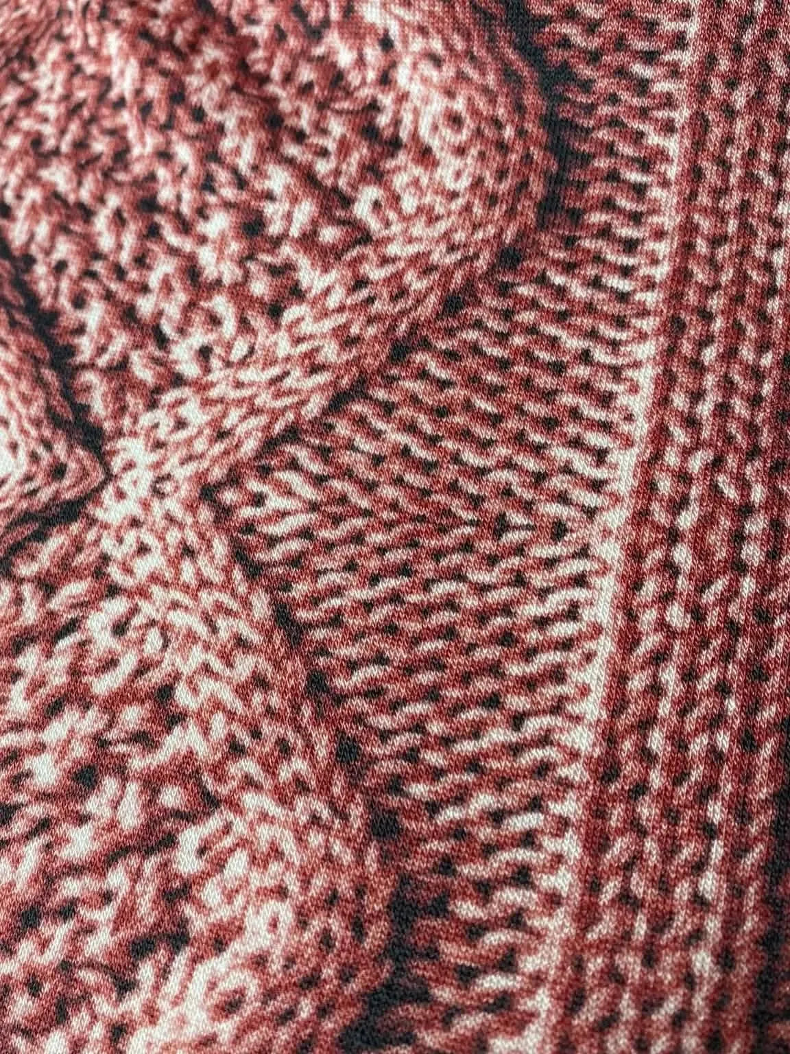Close-up of rose-colored fabric with a detailed cable knit pattern.